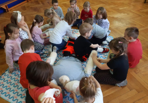 Dzieci obwiązują bandażem nogi, ręce oraz głowę lalki