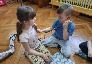 Chłopiec osłuchuje dziewczynkę przy pomocy stetoskopu