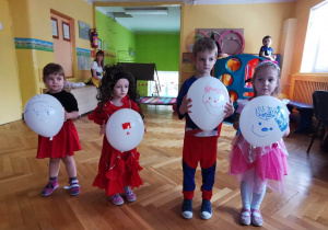 Dzieci pokazują narysowane przez siebie na balonach buźki