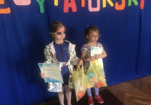 Dwie dziewczynki stoją na podium z nagrodami