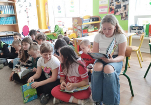 Dziewczynka czyta przedszkolakom swoją ulubioną książkę