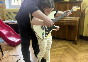 Dziewczynka ćwiczy granie na gitarze