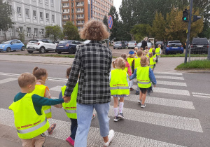 Dzieci przechodzą przez jezdnię na przejściu dla pieszych