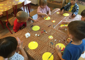 Dzieci przy stolikach wykonują pracę plastyczną