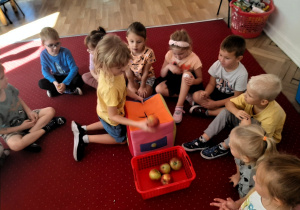 Dzieci szukają w pudle jabłek pomieszanych z piłeczkami