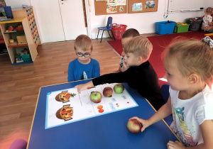 Dzieci układają jabłka na planszy dydaktycznej