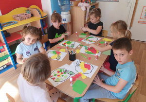 Dzieci wyklejają kontur jabłka kawałkami kolorowego papieru
