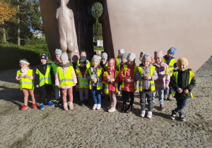 Dzieci stoją pod pomnikiem "Pękniętego Serca"