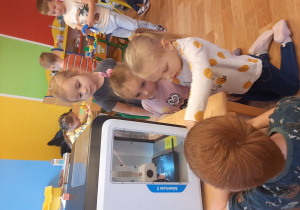 Dzieci obserwują działanie drukarki 3-D
