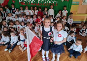 Dwie dziewczynki pozują do zdjęcia trzymając flagę Polski