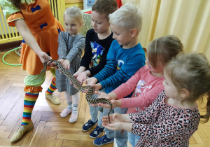 Dzieci trzymają węża na rękach