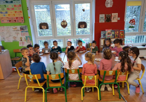 Dzieci siedzą przy stole i degustują herbatkę.