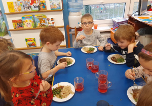 Dzieci jedzą wołowinę z zielonym groszkiem i kaszą