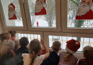 Dzieci obserwują przez okno Mikołaja w ogrodzie