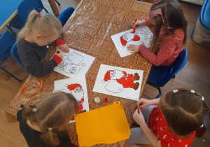 Dzieci wykonują pracę plastyczną o Mikołaju