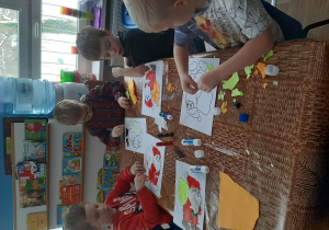 Dzieci wykonują pracę plastyczną o Mikołaju