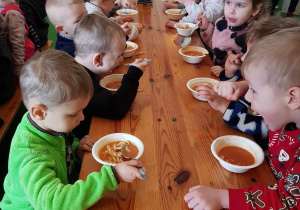 Dzieci jedzą obiad przy wspólnym stole