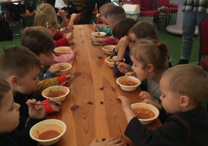 Dzieci jedzą obiad przy wspólnym stole
