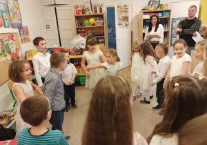Dzieci stojąc w kole śpiewają piosenkę