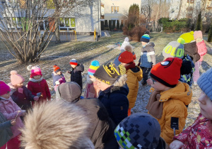 Grupa dzieci stoi na górce w przedszkolnym ogrodzie