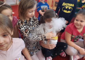 Dzieci podają sobie słoik, z którego wydobywa się dym