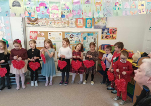 Dzieci śpiewają piosenkę trzymając w rękach papierowe serca