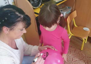 Babcia maluje podobiznę wnuczki na balonie