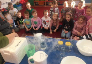 Dzieci obserwują doświadczenie chemiczne z parującycm suchym lodem