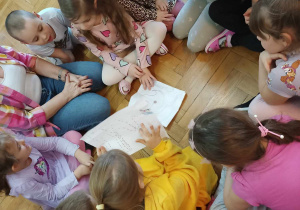 Dzieci oglądają na podłodze mapę.