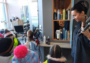 P.fryzjerka pokazuje dzieciom przybory do pracy.