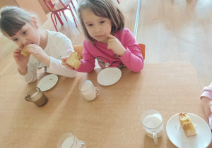 Dzieci jedzą przy stoliku ciasto upieczone przez p kucharki.
