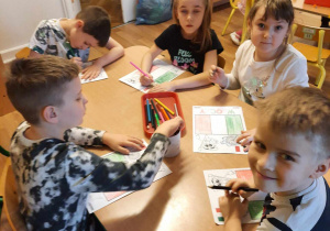 Grupa dzieci koloruje przy stole.