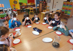 Dzieci siedzą przy stole i piją cafe.