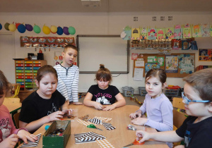 Grupa dzieci siedzi przy stoliku i tnie materiał.