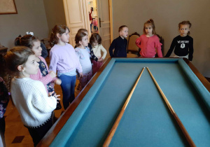 Grupa dzieci ogląda stół do bilarda