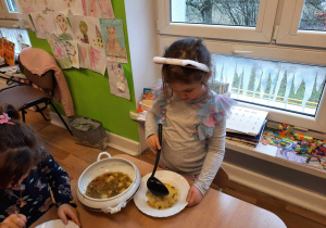Dziewczynka nalewa zupę z wazy.
