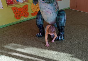 Dziewczynka wykonuje ćwiczenia z dinozaurem