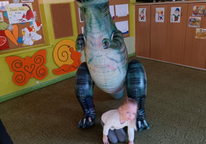 Dziewczynka wykonuje ćwiczenia z dinozaurem