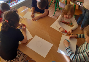 Dzieci rysują dinozaura z figur geometrycznych