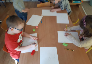 Dzieci rysują dinozaura z figur geometrycznych