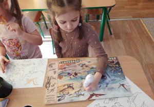 Dziewczynka przegląda książkę o dinozaurach