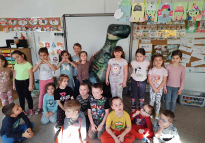 Dzieci pozują do zdjęcia z dmuchanym dinozaurem