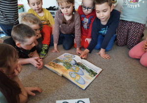 Dzieci przeglądają książkę z dinozaurami