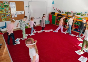 Dzieci chodzą po wykonanych przez siebie śladach stóp dinozaurów