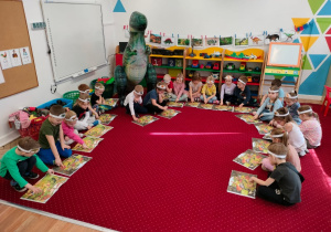 Dzieci oglądają karty pracy z dinozaurami