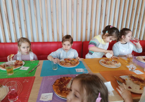 Grupa dzieci je pizzę.