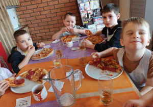 Grupa dzieci je pizzę.