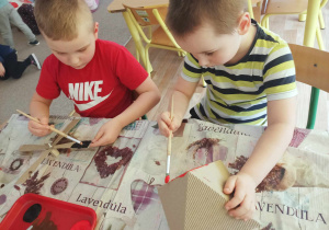 Chłopcy malują elementy papierowego wiatraka