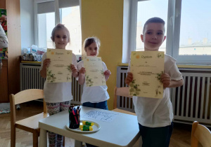 Troje dzieci pokazuje dyplomy za udział w konkursie