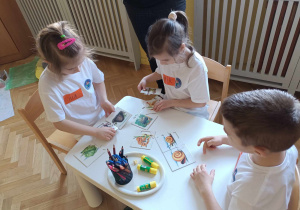 Troje dzieci układa karty sekwencyjne